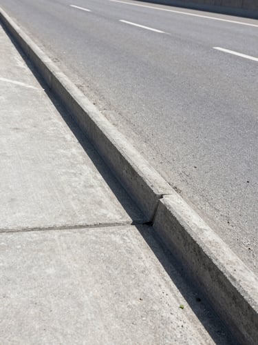 Close-up wide shot of a reinforced concrete expansion joint on a completed highway bridge deck, bright midday daylight, sharp structural detail visible across the full horizontal frame, neutral grey concrete texture, no workers, no equipment