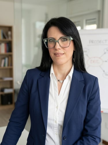 Professional businesswoman in a blue blazer and glasses standing in a bright office.