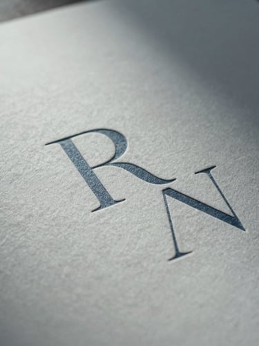Extreme close-up of bespoke printed collateral on heavy-weight cotton paper, showcasing deep blind debossing of minimalist serif letters, soft cool northern light, quiet shadow.