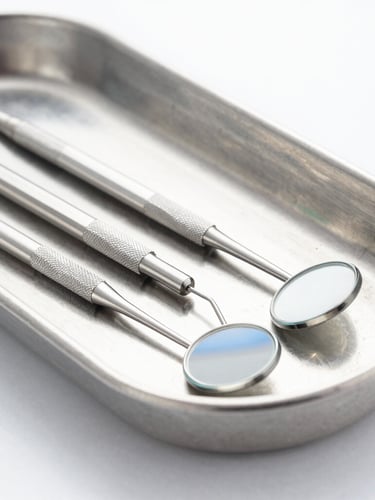Macro shot of high-precision dental explorers and mirrors lying on a sterile light gray metal tray, bright high-key studio lighting, clinical white and blue tones, sharp focus
