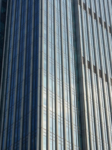 A striking modern skyscraper facade in Jakarta, sharp architectural angles of glass and steel reflecting the blue sky and golden sunlight, clean corporate aesthetic, crisp corporate photography, 35mm lens