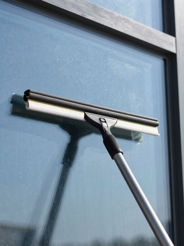Close-up of professional squeegee cleaning a large glass window, sparkling clean glass, bright natural daylight, crisp focus