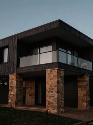 Wide-angle architectural elevation of a modern coastal home in Sydney, showing sandstone foundations protected from damp, dramatic low-key lighting, deep charcoal tones