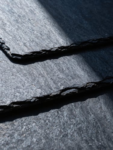 Macro architectural detail of interlocking slate panels, sharp directional light, high contrast, cool slate and deep navy tones, 35mm