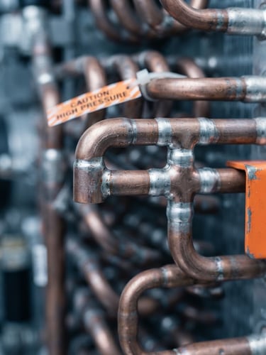 Macro photograph of a copper refrigeration coil with precise solder joints, cool metallic tones, sharp focus, 50mm lens