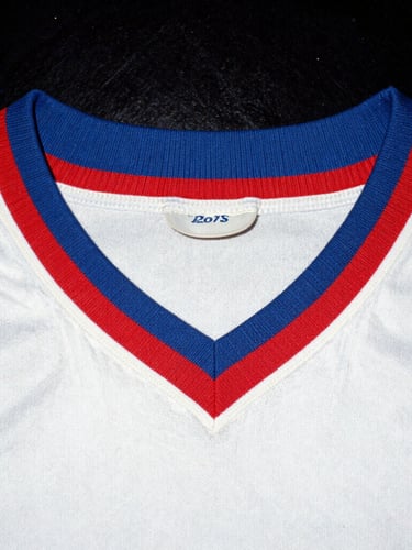 Candid 35mm film photo of a vintage football shirt collar close-up, heavy grain, harsh direct flash, authentic 90s aesthetic