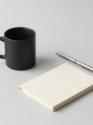 A minimalist flat-lay of a matte black ceramic mug, a brushed aluminum pen, and an organic cotton notebook on a neutral gray background, clean studio lighting, soft shadows