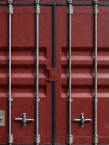 Close-up of secured shipping container latches and custom seals, sharp industrial photography, deep crimson tones, high-contrast daylight