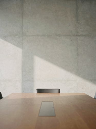 Minimalist architectural detail of an empty high-end boardroom, soft indirect daylight casting long shadows on a concrete wall, 35mm photography