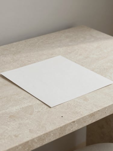 Tactile paper mockups and architectural details on a minimalist ivory stone desk under soft, low-contrast north-facing daylight, 35mm.