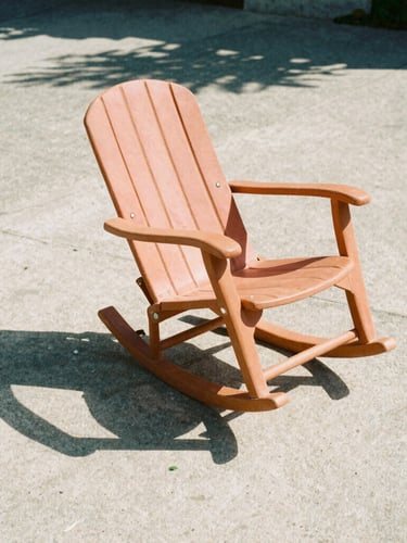 Low-angle architectural shot of a single terracotta rocker casting a sharp graphic shadow on raw concrete, harsh direct mid-afternoon sunlight, 35mm film style.