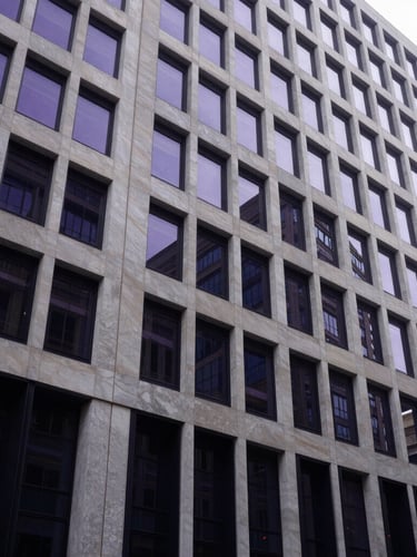 Wide-angle architectural framing of a modern corporate building facade in Madrid, clean geometric lines, natural diffused daylight, soft purple and deep navy reflections, 35mm.