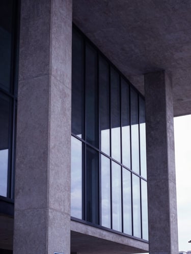 Low angle architectural shot of modern concrete and glass columns, soft natural light, minimalist corporate environment, 35mm