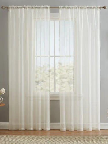 Elegant sheer white curtains hanging on a bronze rod over a window in a gray room.
