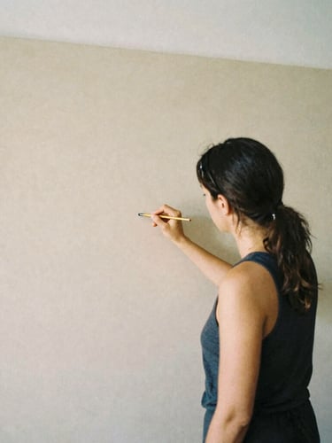 A professional female artist in her Lisbon studio, working quietly on a large neutral canvas, soft natural daylight, editorial 35mm film aesthetic