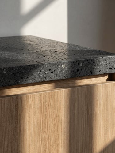 A sharp, tactile architectural detail crop of dark travertine stone and raw oak wood paneling under soft morning window light, high-contrast shadows.