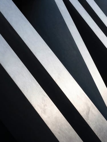 Abstract high-contrast architectural geometry with strong leading diagonal lines, cool silver tones, deep slate shadows.