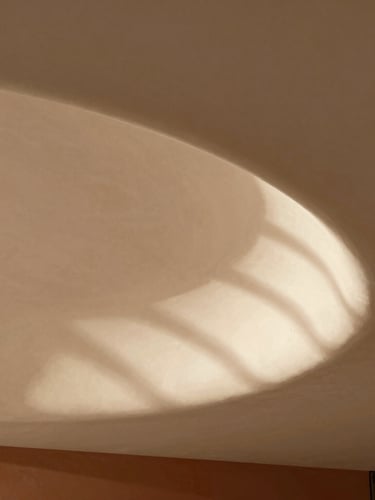 Close-up of a contemporary architectural detail, elegant curved plaster ceiling, soft natural daylight casting subtle geometric shadows, warm sand tones, minimalist aesthetic