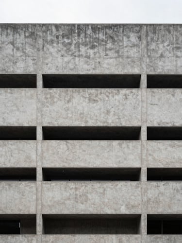 Sober architectural photography of a modern concrete building facade in Bogota under crisp overcast daylight, symmetrical composition, desaturated cool tones