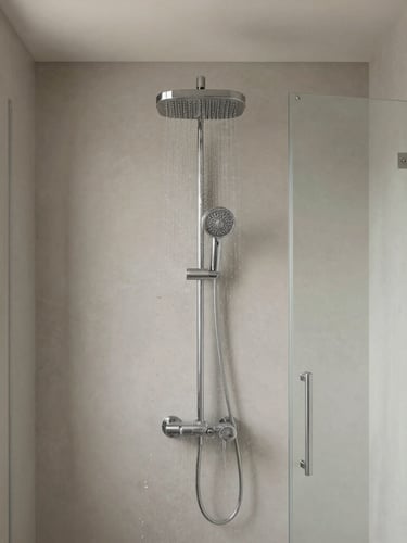 Straight-on architectural shot of a modern tanked wet room with a rain shower head, clean glass panel, soft warm-grey tones, bright natural light.