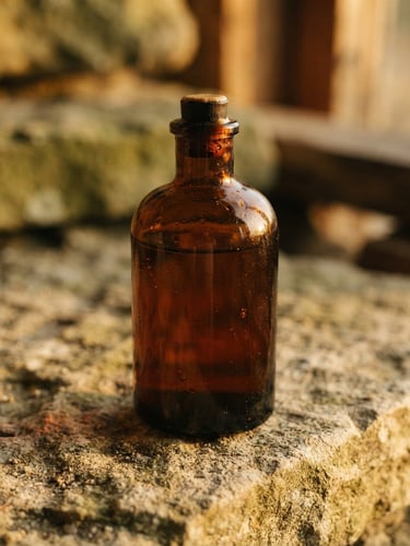 Macro close-up of a dark amber glass bottle of AUREON on a raw stone surface, warm golden-hour side light, soft shadows, editorial photography, 35mm