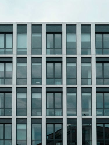 Wide environmental architectural shot of a modern UK commercial property facade, clean corporate lines, overcast daylight, desaturated teal tones.