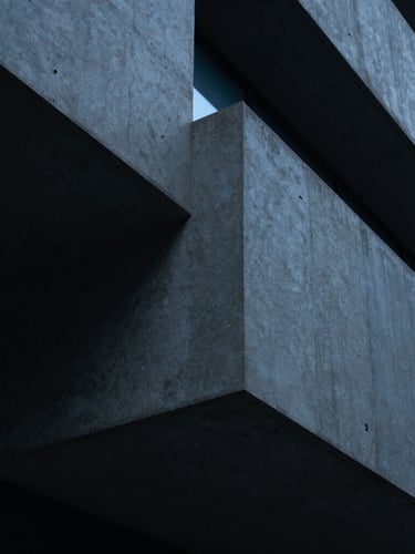 Abstract architectural geometry representing structure, close-up of sharp concrete angles, cool low-key corporate lighting with subtle blue ambient glows, 35mm