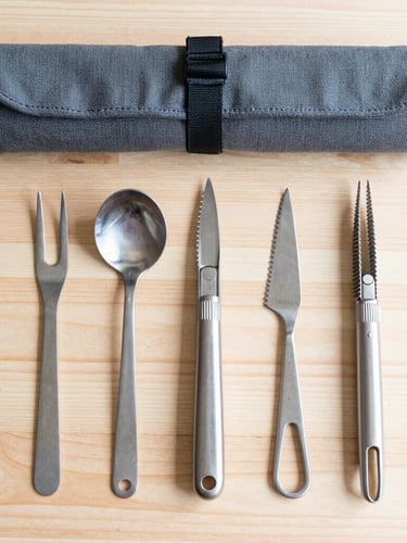 Overhead flat lay of high-quality stainless steel tools and a durable canvas utility roll on a clean wooden workbench, bright natural morning light, sharp focus, 50mm lens