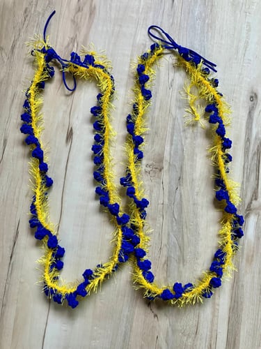 2 royal blue and yellow leis lying side by side