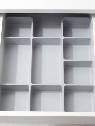 Straight-on orthographic shot of a perfectly organized kitchen drawer containing modular gray dividers, bright high-key product photography, clean white background, crisp studio light, sharp focus, 50mm