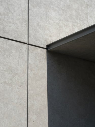 Overcast daylight on a concrete facade with sharp geometric shadows, minimalist steel lines, architectural crop.