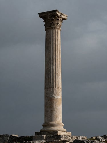 A wide, isolated environmental shot of a single classical stone pillar standing against an overcast, moody sky. Low-key dramatic lighting, deep shadows, high-contrast, evoking ancient wisdom and timeless authority.
