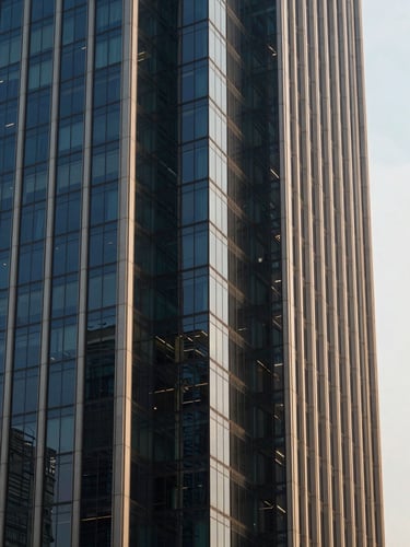 Sharp close-up of architectural glass and steel of a Jakarta high-rise, cool morning light reflecting deep navy tones, premium corporate editorial style, 35mm