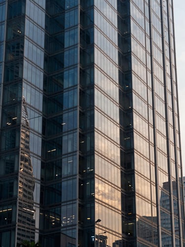 Sharp architectural photography of modern high-rise glass facade in Jakarta CBD, cool morning light, deep navy reflections