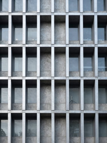 Symmetrical architectural detail of a modern concrete and steel building facade, high contrast, cool metallic silver tones, clean linear grid.
