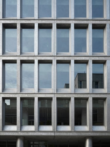 Symmetrical architectural shot of a modern concrete and steel office facade, cool morning daylight, metallic silver reflections, minimalist lines, generous negative space.