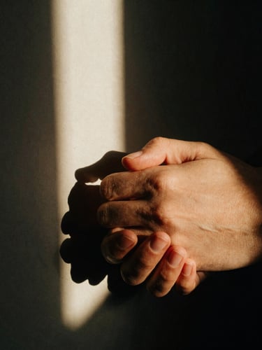 Extreme close-up of a couple's hands gently intertwined, moody directional window light, heavy shadows, warm film grain, 35mm cinematic composition