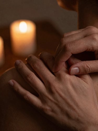 Close-up of hands applying precise, firm pressure on a shoulder, soft low-key candlelight, warm earthy tones, shallow depth of field, 35mm