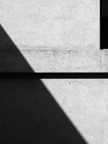 Minimalist architectural crop of a modern concrete building facade in Manila, sharp shadows, high contrast black and white, 35mm lens.