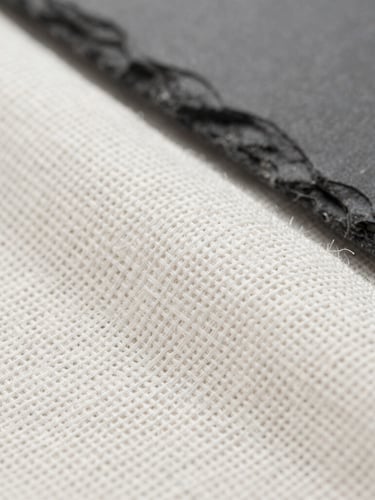 Macro close-up of premium white linen textile weave, bright neutral studio light, sharp focus on fabric threads, high-contrast slate tones
