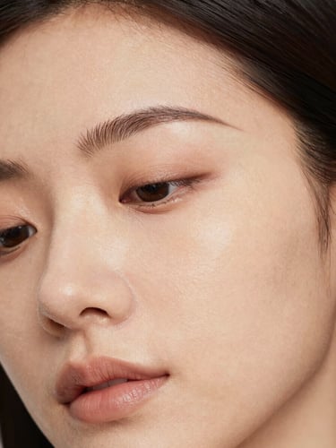 Close-up of relaxed, smooth forehead skin with natural radiance under identical soft warm studio lighting, 35mm clinical aesthetic