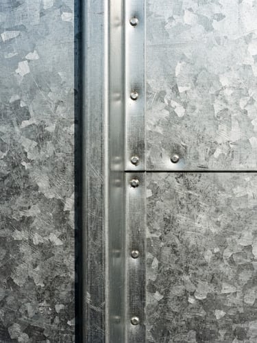 Close-up of clean metal seams on a galvanized steel sheet, sharp focus, hard direct sunlight, industrial documentary style