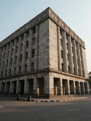 Wide environmental shot of brutalist New Delhi institutional architecture, geometric shadows on stone, soft diffused north-facing daylight.