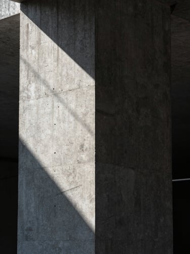 A close-up portrait of a brutalist concrete pillar with sharp geometric shadows and cool ambient light, suggesting hidden structural integrity.