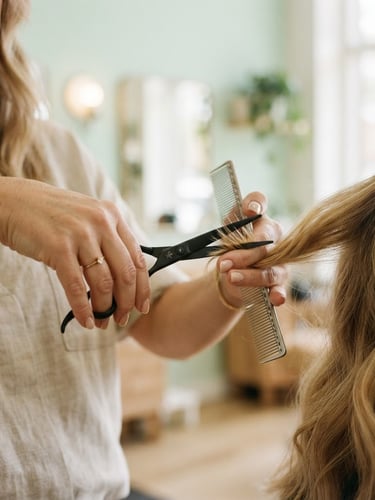 Close-up of a certified stylist's hands holding specialized quiet shears, soft diffused natural indoor light, gentle pastel mint background, shallow depth of field, 35mm