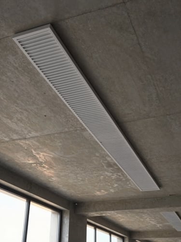 Sleek, minimal linear slot diffuser integrated into a raw concrete ceiling, casting subtle cool air refraction, warm sunlight through high windows.