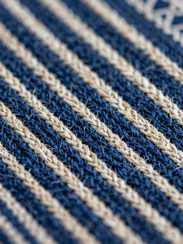 Extreme close-up macro of a hand-woven Indonesian textile surface, warp and weft threads in deep indigo and natural undyed cotton clearly distinct, north-facing natural daylight, no flash, sharp detail across the full frame