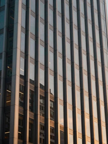 Architectural crop of a modern financial district skyscraper facade, clean steel and glass lines reflecting soft daylight, professional corporate atmosphere, 35mm.