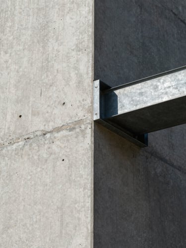 Extreme close-up of a raw board-formed concrete wall meeting a sharp steel beam under harsh, direct midday sunlight, casting deep architectural shadows.