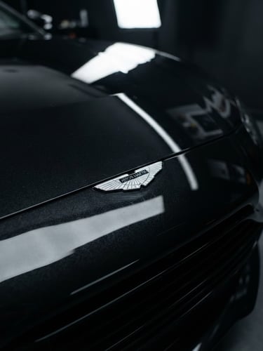 Sleek automotive photography of a sports car hood with sharp reflections under studio lighting, deep metallic black tones, macro lens detail, 35mm